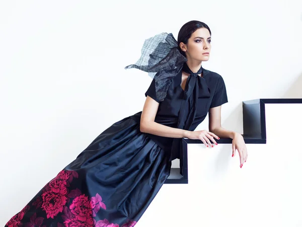 Woman in black shirt and long skirt with floral print posing on stairs