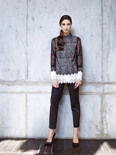 Fashion model wearing black lace shirt and trousers posing in studio