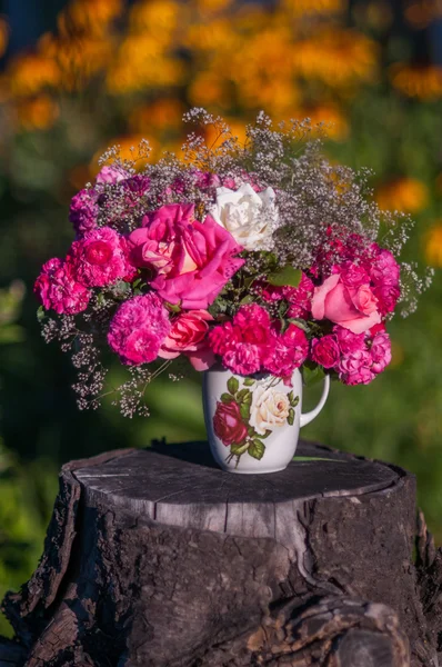 Beautiful bouquet of roses in the vase on the stump with green background