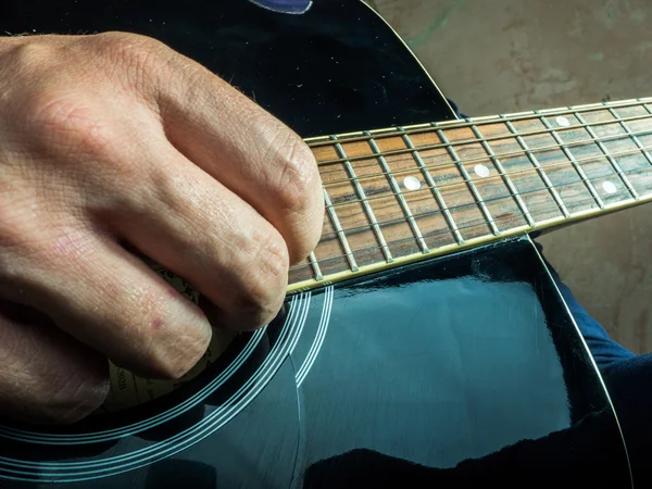 Closeup photo of an acoustic guitar played by a man.