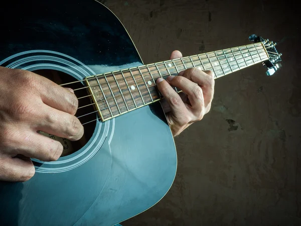 Closeup photo of an acoustic guitar played by a man.
