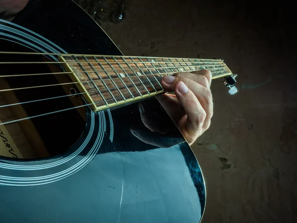 Closeup photo of an acoustic guitar played by a man.