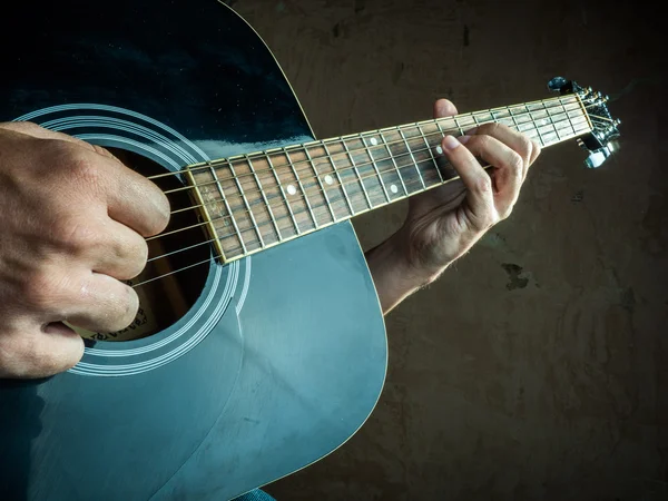 Closeup photo of an acoustic guitar played by a man.