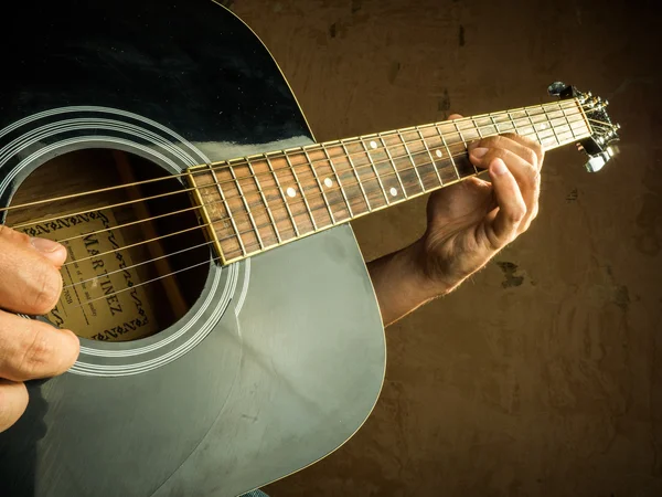 Closeup photo of an acoustic guitar played by a man.