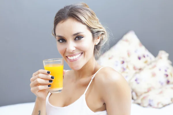 Relaxed woman drinking orange juice at home in bedroom