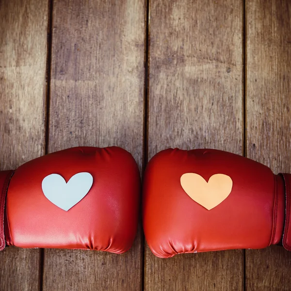 Hearts on red boxing gloves on wood. Conceptual image of fight f