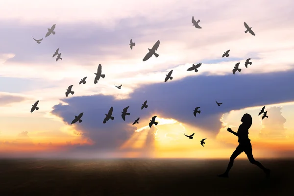 Girl feeling freedom on field during sunrise, birds flying around