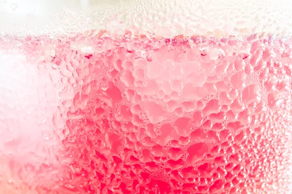 Pink bubbles illuminate from cold drink, abstract background.