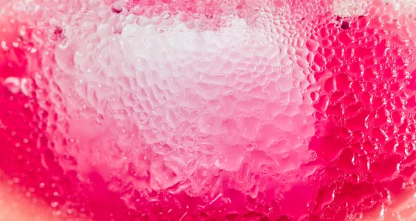 Pink bubbles illuminate from cold drink, abstract background.