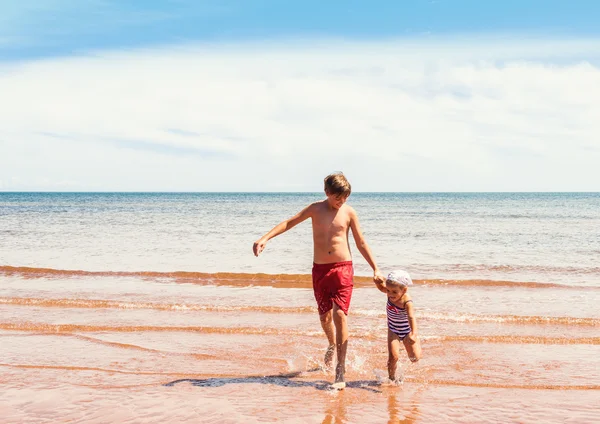 Little girl and boy playing on the beach