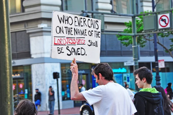 San Francisco, California: a man shows a sign with a religious phrase