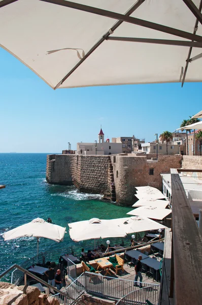 Israel: Acre Sea Walls trough the outdoor umbrellas of a restaurant