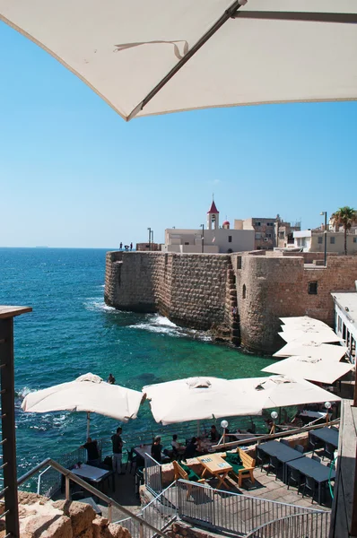 Israel: Acre Sea Walls trough the outdoor umbrellas of a restaurant
