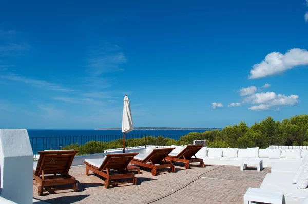Fomentera, Balearic Islands: panoramic view of Mediterranean Sea and Mediterranean maquis seen from a white terrace with deck chairs