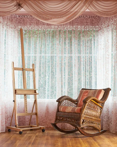 Wicker rocking chair and wooden easel composition