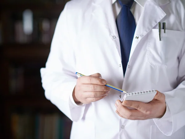 Man in a white doctor's coat writing down