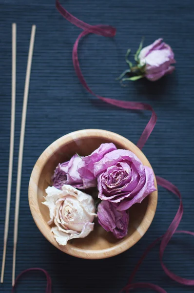 Dried roses in wooden bowl and aroma sticks