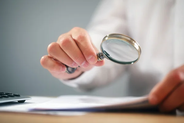 Businessman with magnifying glass reading documents