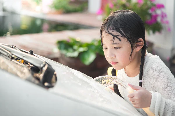 Beautiful asian child washing car