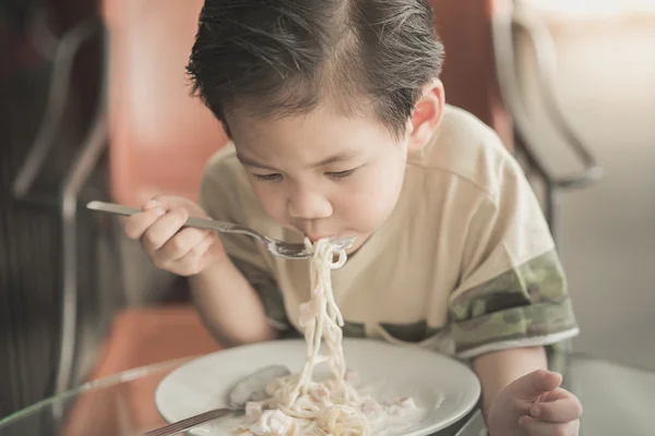Cute Asian chid eating Spaghetti Carbonara