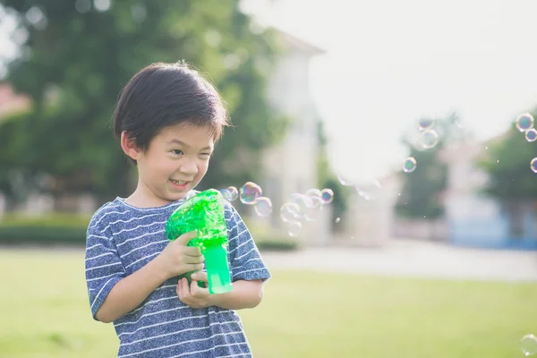 Asian child Shooting Bubbles from Bubble Gun