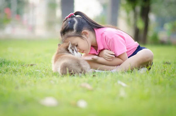 Beautiful asian girl playing on green grass with a puppy