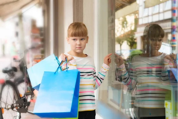 Sad little  girl pointing to shop window