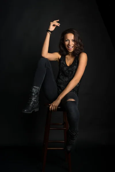 Beautiful brunette woman in jeans sitting on a chair and laughin