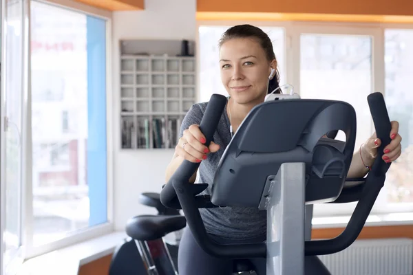 Happy woman is engaged on a stationary bike