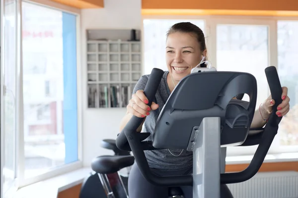 Happy woman is engaged on a stationary bike