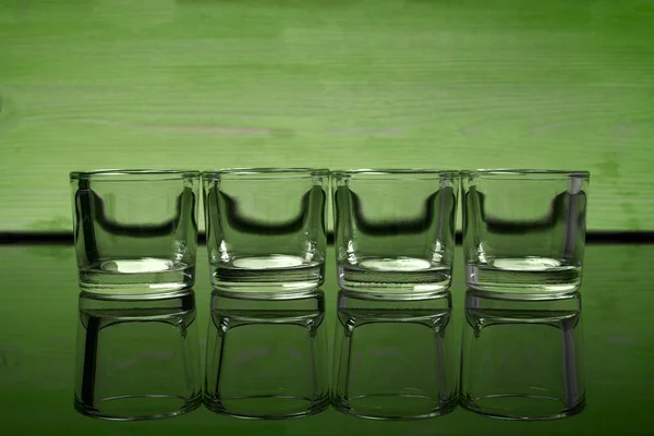 Empty glasses of vodka on a green background