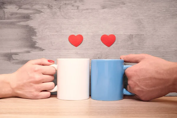 Hands loving couple holding cups with hearts
