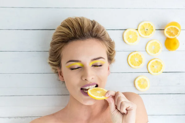 Blonde woman laying next to slices of lemon