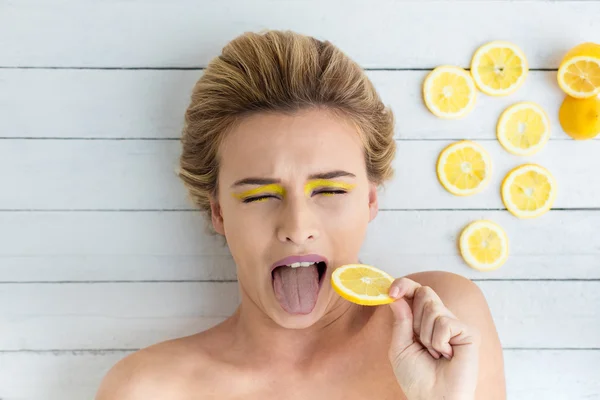 Blonde woman laying next to slices of lemon