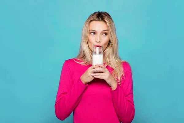 Blonde young woman a glass of milk on blue