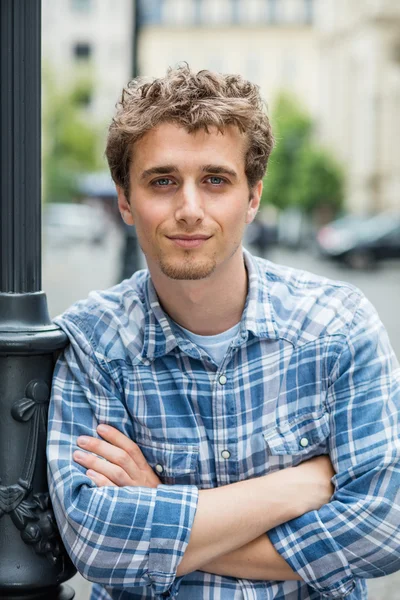 Young man in checkered shirt standing outside
