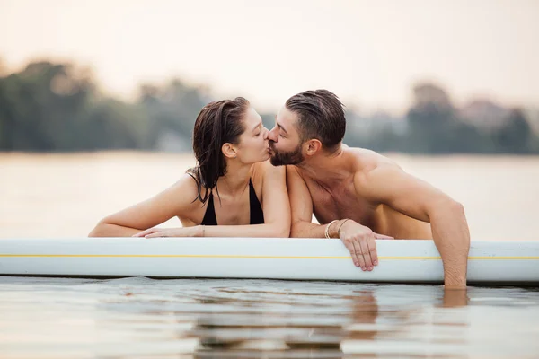 Man and woman relaxing in water on a paddleboard