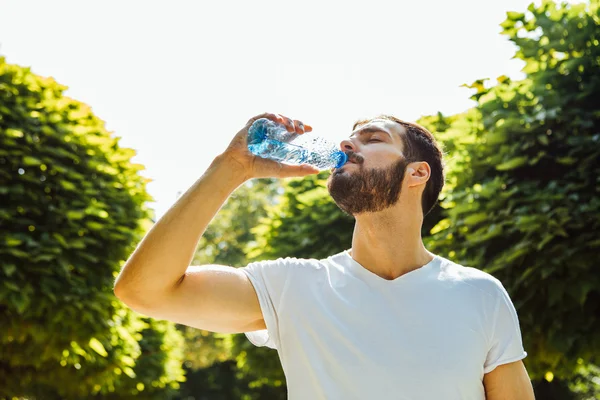 Adult man drinking water from a bottle outside