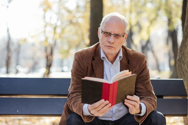 Old elegant man reading a book outside