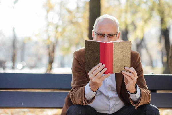 Old elegant man reading a book outside