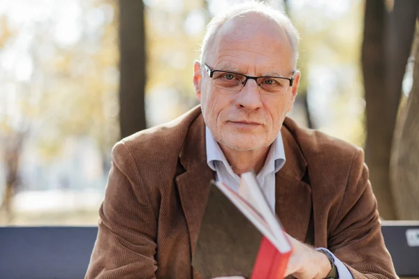 Old elegant man reading a book outside