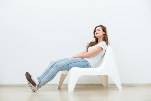 Single woman sitting on white chair