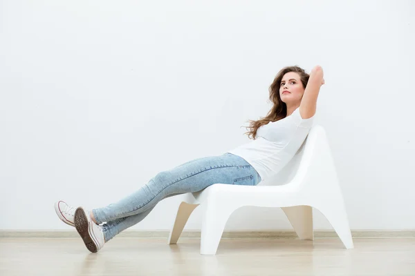 Single woman sitting on white chair