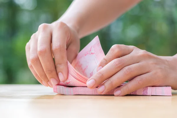 Woman hand counting thai cash on wood table