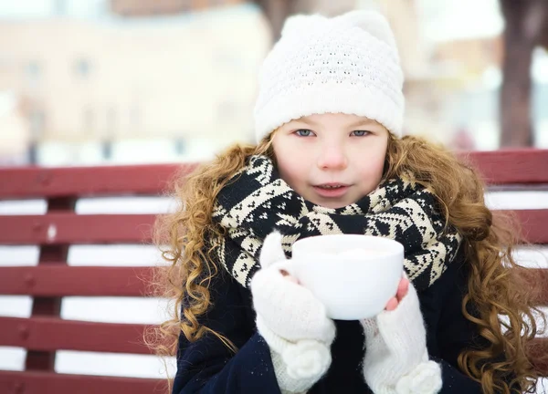 Little girl heated hot coffee frosty winter in snow-covered park
