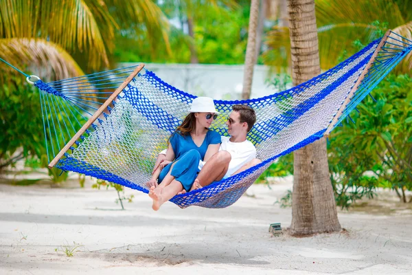 Happy couple on summer vacation relaxing in hammock