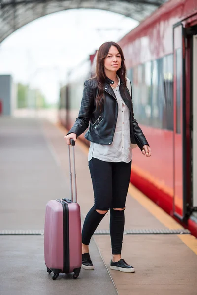 Young woman with luggage talking at train station. Caucasiam tourist waiting her express train while her vacation