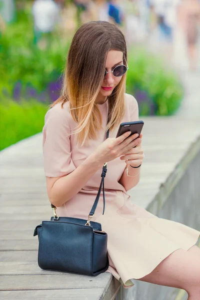 Tourist girl sending messgae by smartphone on summer holidays. Young attractive woman with mobile phone outdoors enjoying holidays travel destination in tourism and exploring concept