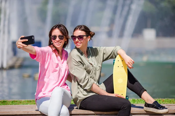 Caucasian girls making selfie background big fountain. Young tourist friends traveling on holidays outdoors smiling happy.