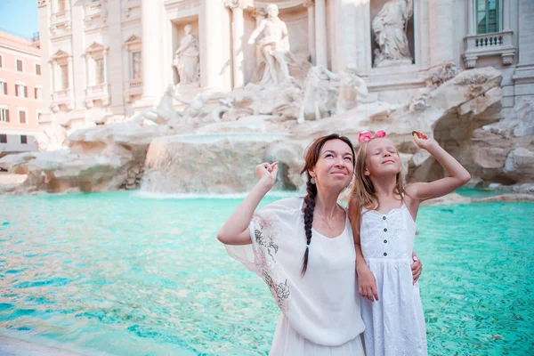 Travel family mom and girl trowing coin at Trevi Fountain, Rome, Italy for good luck. Happy family enjoy their italian vacation holiday in Europe. Little girl making a wish to come back.